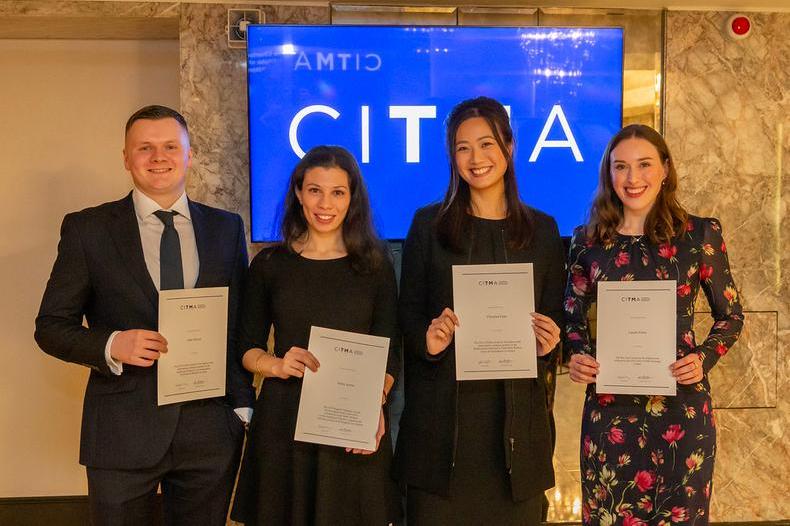 five people, four with certificates, in front of the citma logo